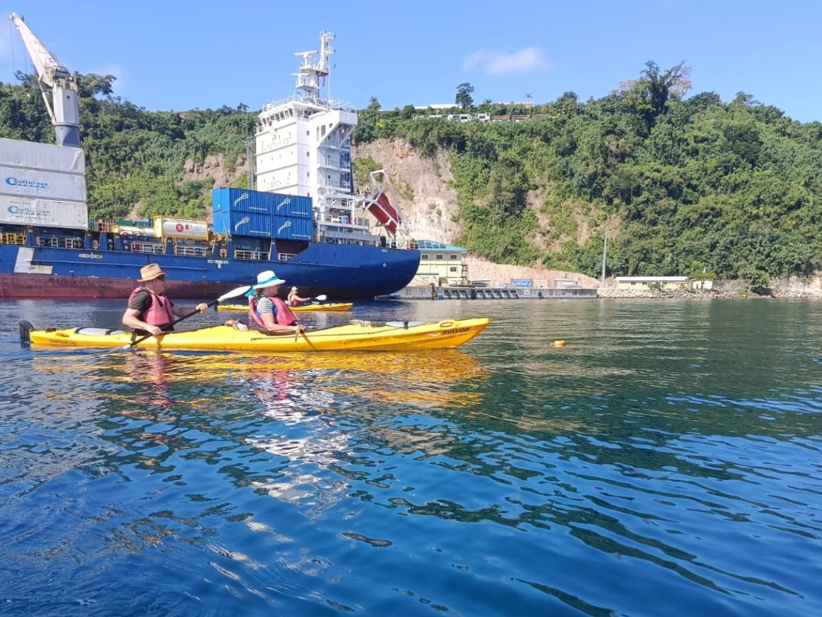 Kayakers paddling past Port Vila harbour with tropical cliffs behind