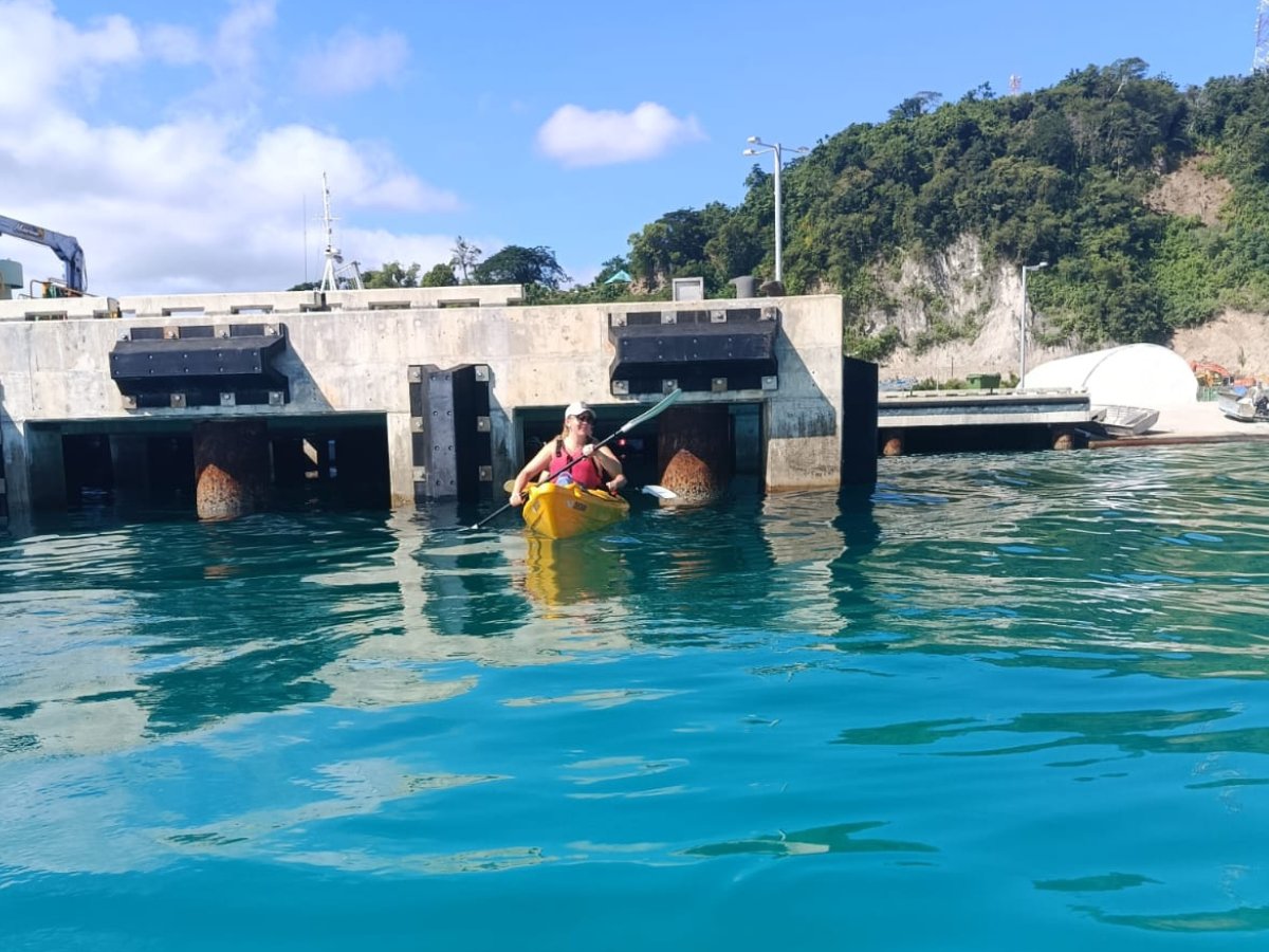 Guest kayaking beneath a pier on the coastal paddle to Paradise Cove