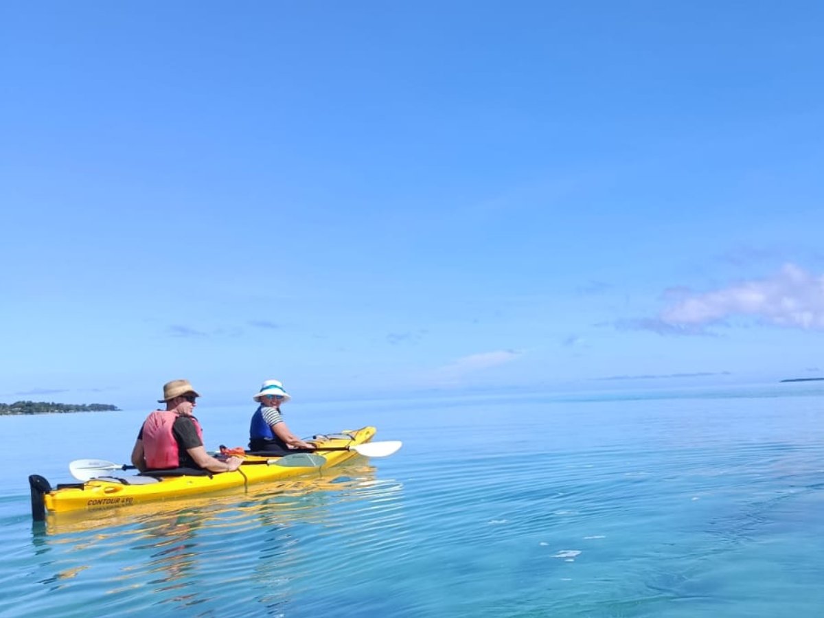 Guests smiling in a tandem kayak on the full-day Paradise Cove paddle
