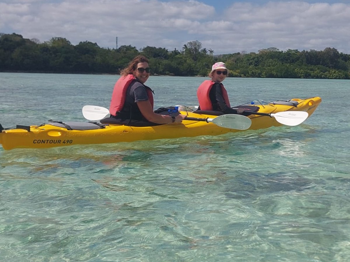 Guests smiling in a tandem kayak on calm harbour water
