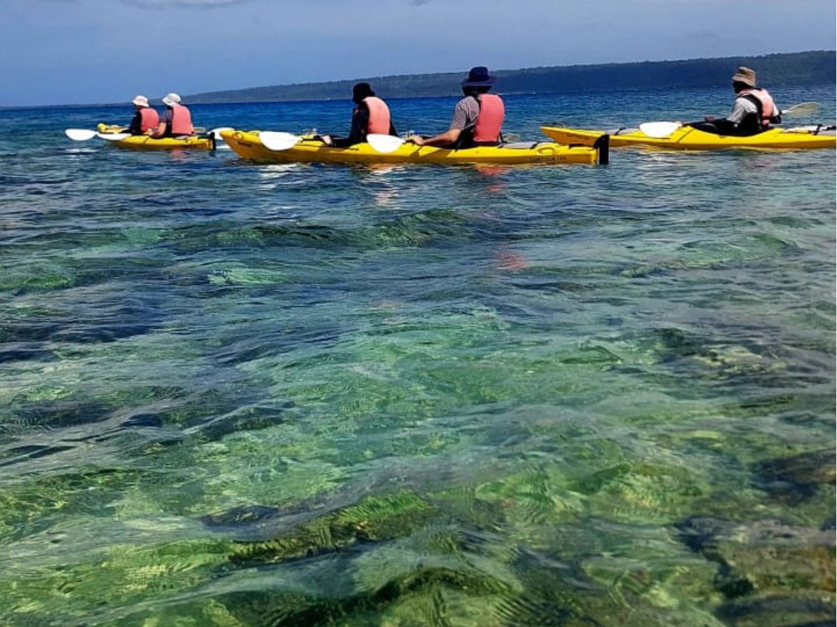 Group kayaking over clear reef water in Port Vila harbour