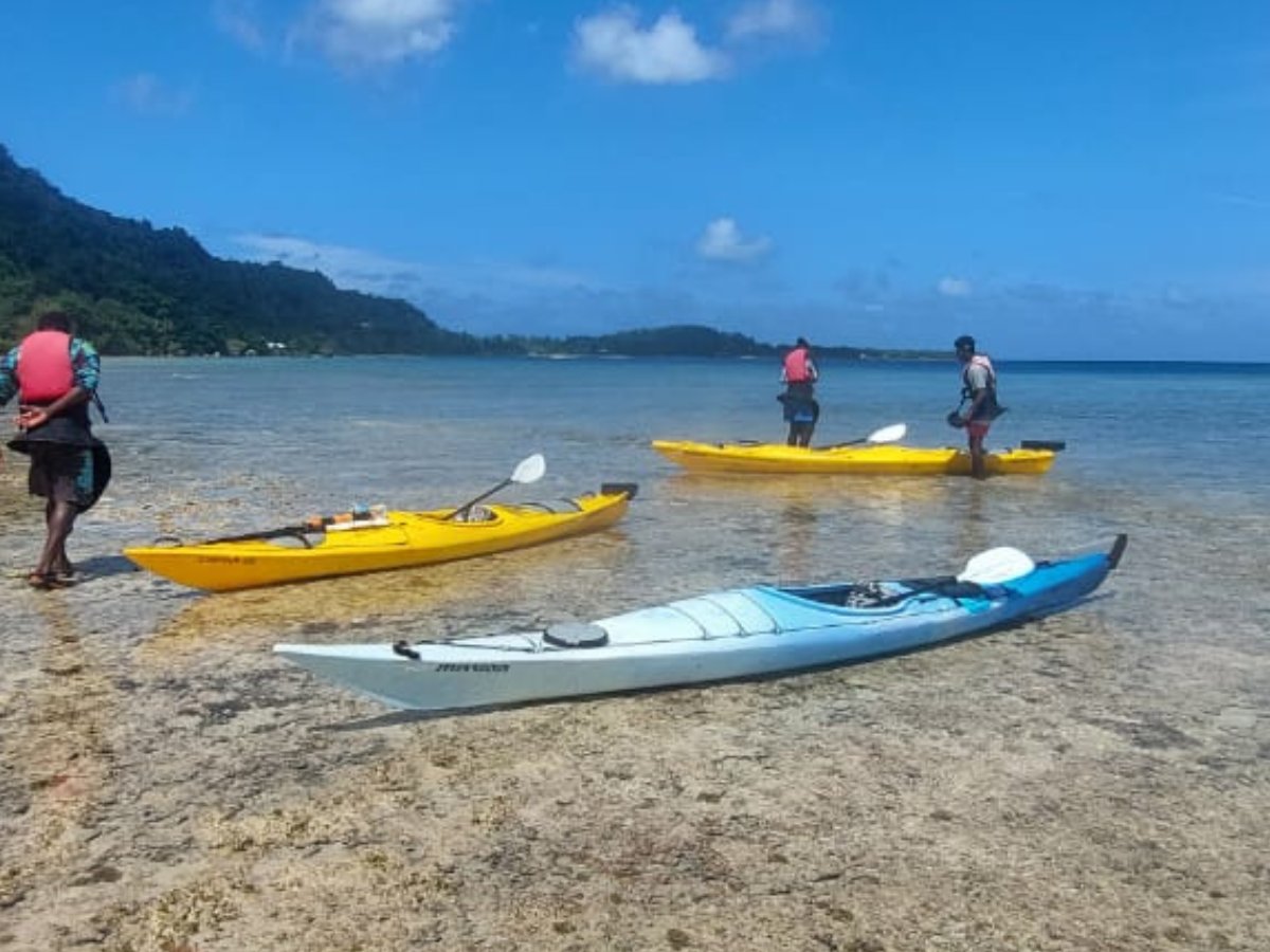 Kayakers preparing in shallow clear water near the harbour