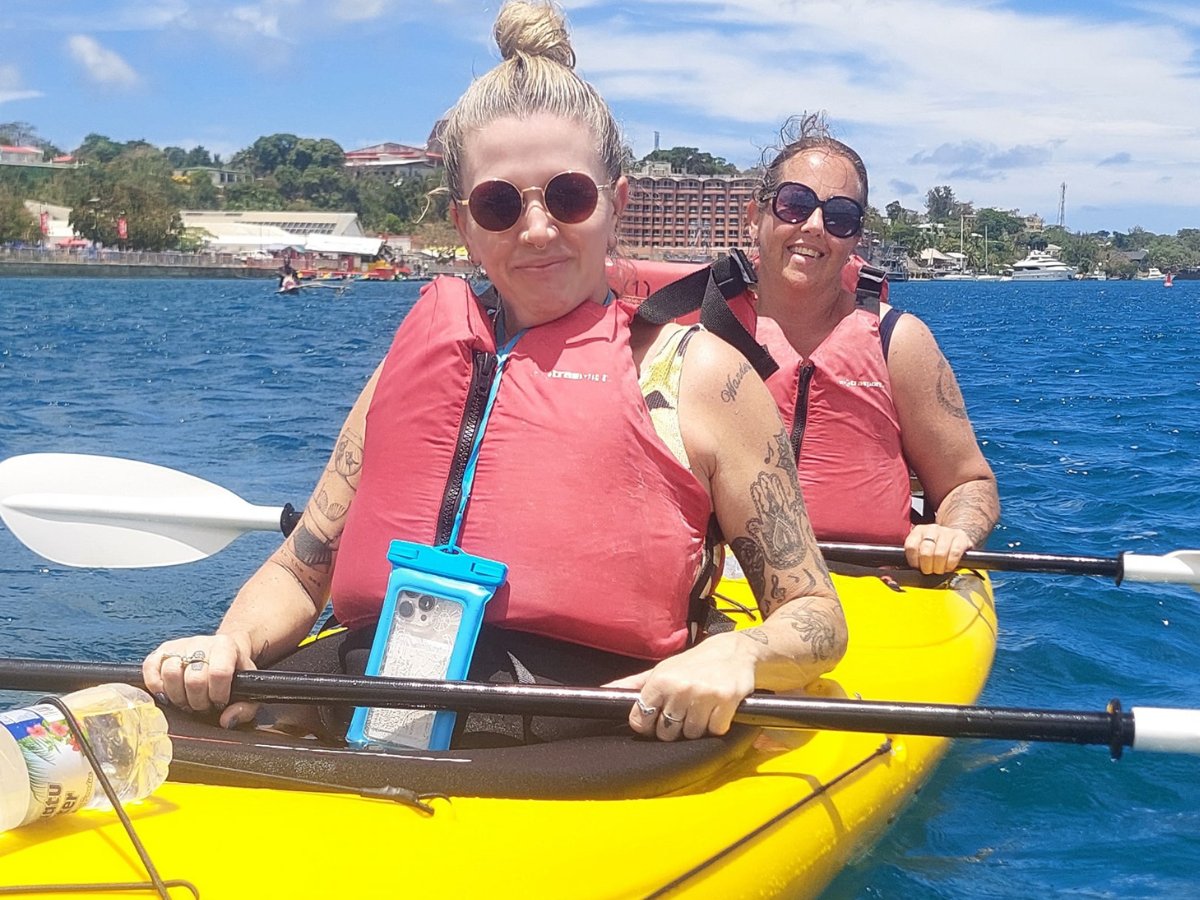 Two guests paddling a tandem kayak past Port Vila shoreline