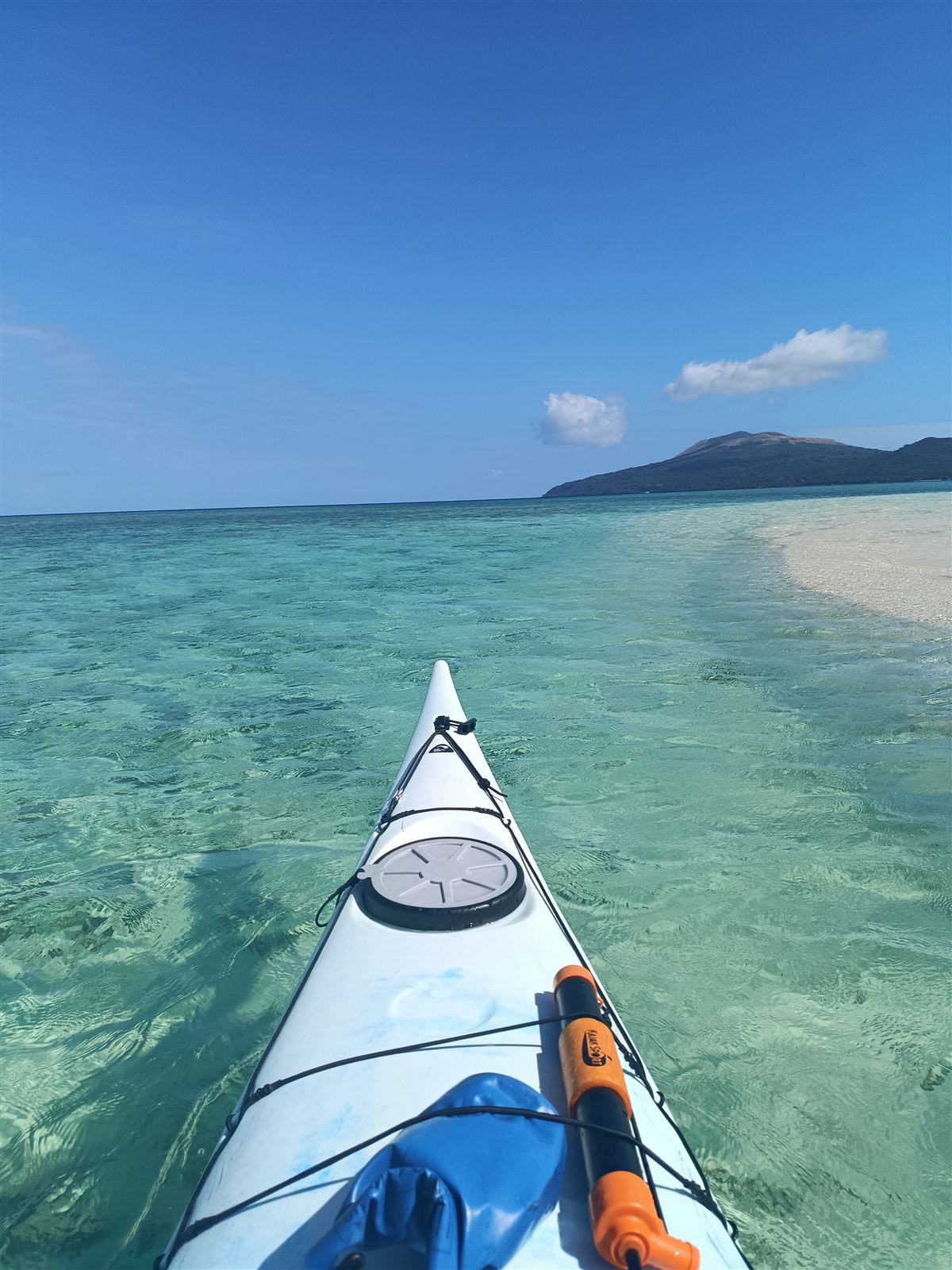 Kayak bow over clear seagrass shallows off Kakula
