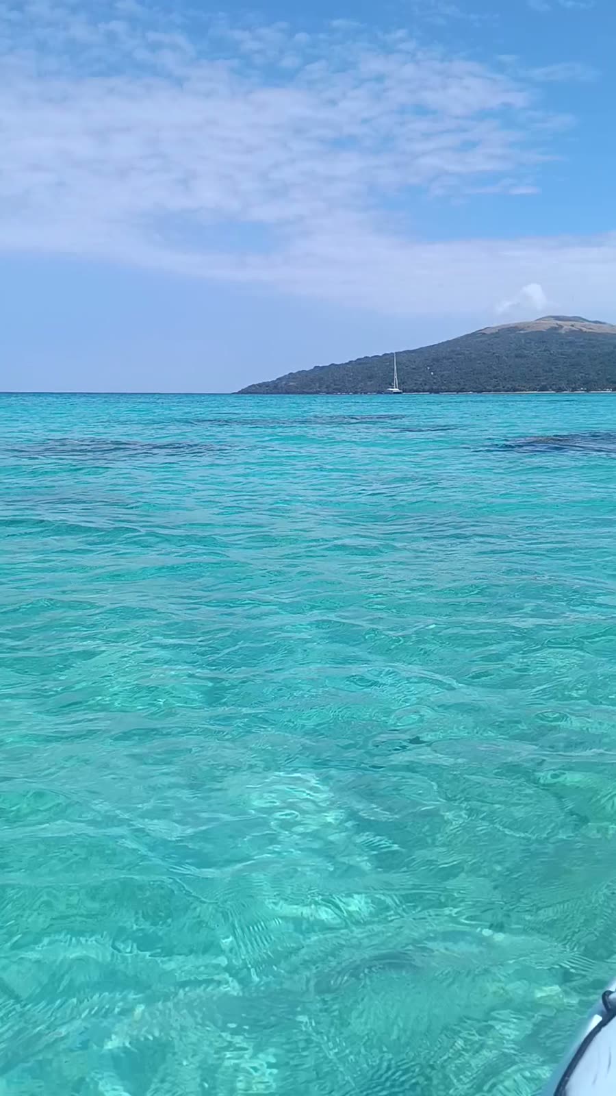 Bright turquoise water off the green hills of Pele Island