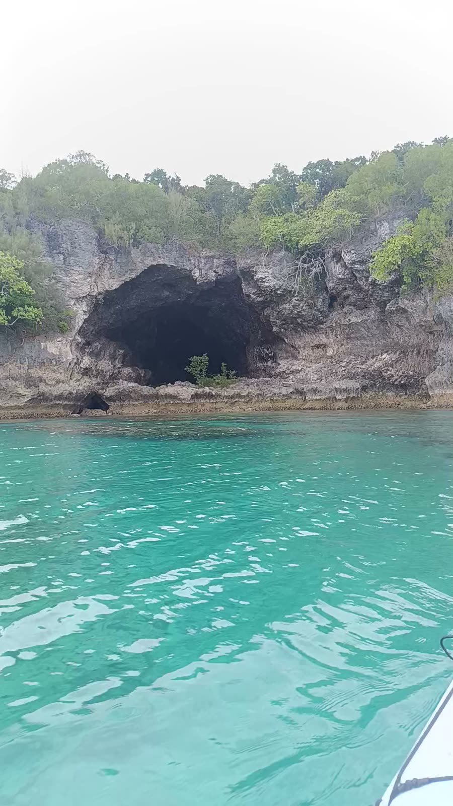 Sea cave in the limestone cliffs of Moso above glowing turquoise water