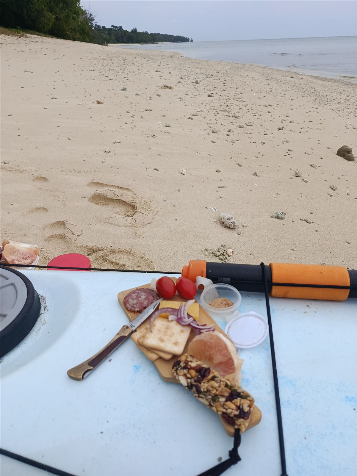 Lunch of tomatoes and crackers laid out on the kayak deck on the beach