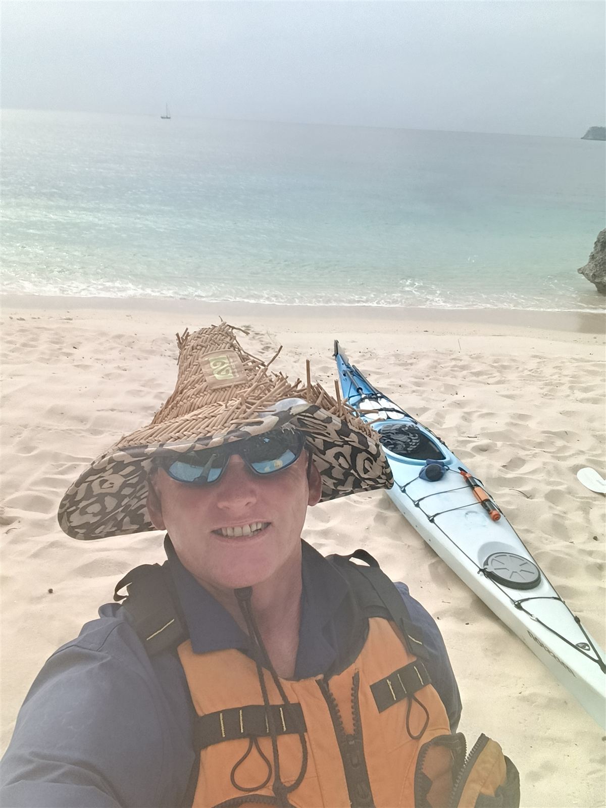 Your Kayak Vanuatu guide in a woven hat and life jacket on the sand at Hapi Tok Beach, with his sea kayak behind