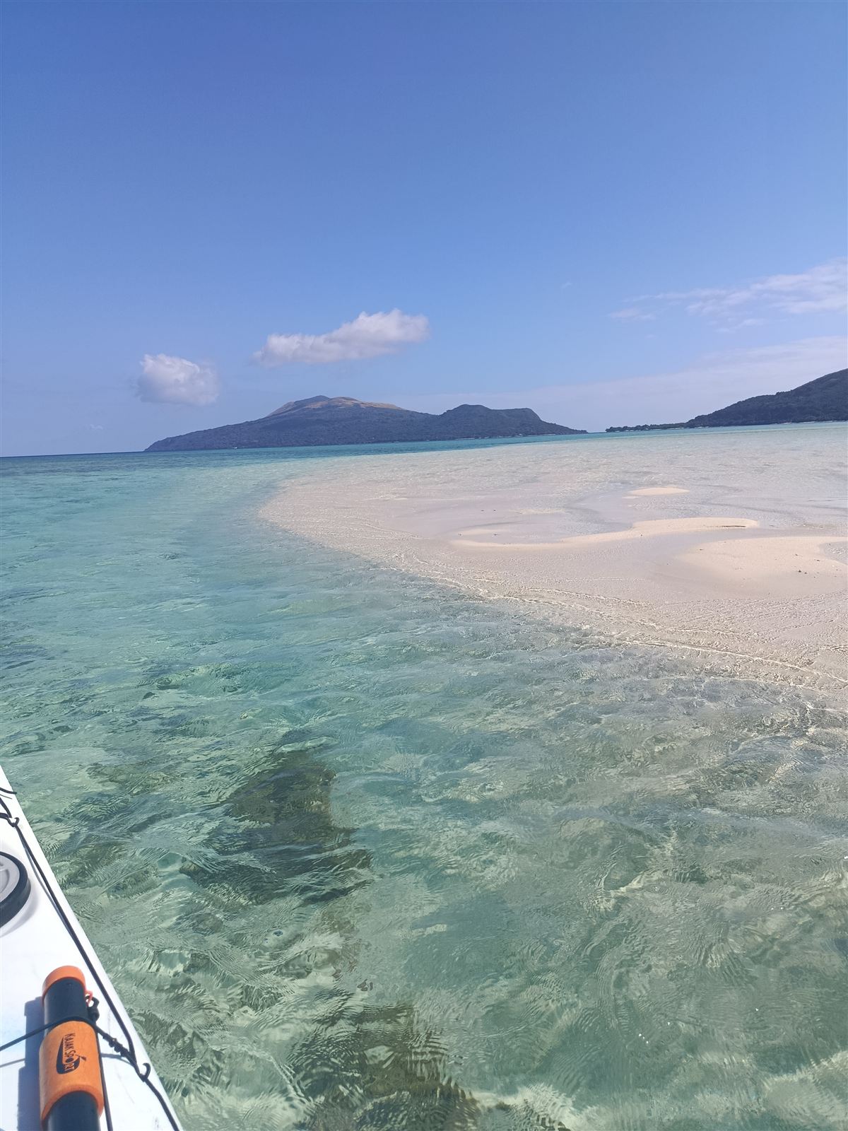 Sea kayak gliding over clear turquoise water beside the Kakula sandbar, with Nguna and Pele behind
