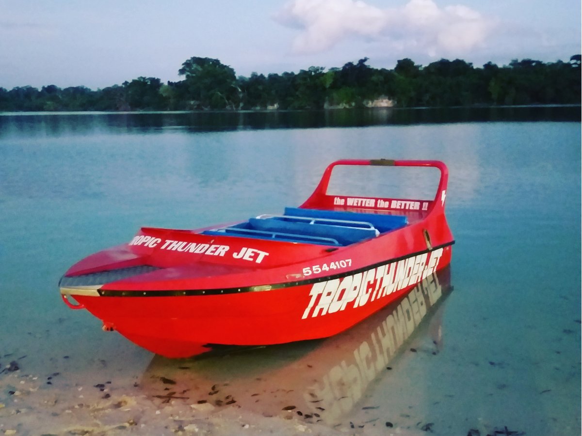 Red Tropic Thunder Jet boat on calm reflective water