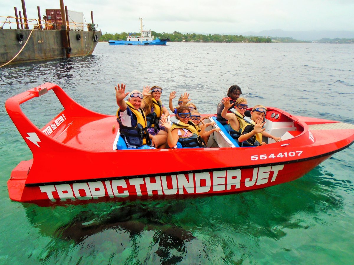 Guests waving from the Tropic Thunder Jet on clear harbour water